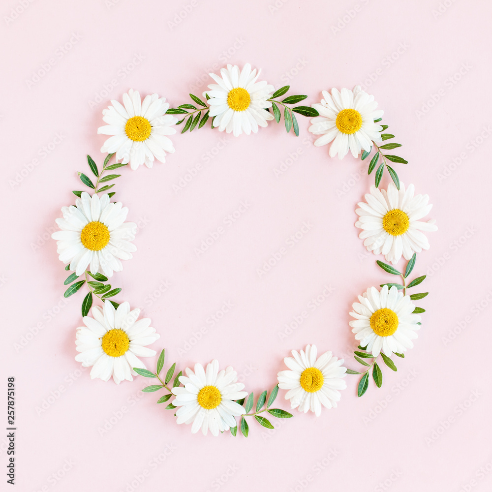 Round frame, wreath made of chamomiles, petals, leaves on beige background. Flat lay, top view