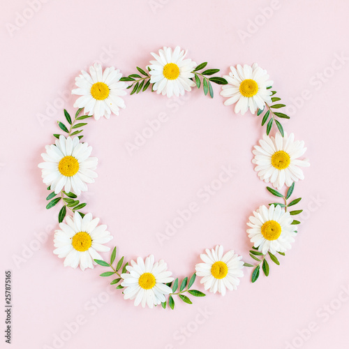 Round frame, wreath made of chamomiles, petals, leaves on beige background. Flat lay, top view © K.Decor