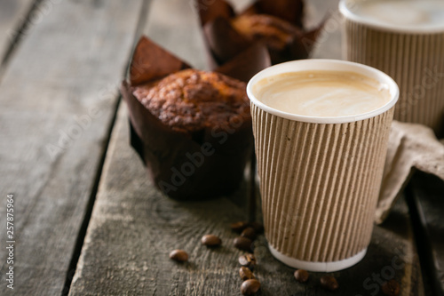 Coffee to go with muffin on wood background, copy space
