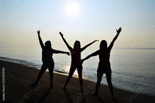 Silhouette of 3 ladies with sunrise on the beach