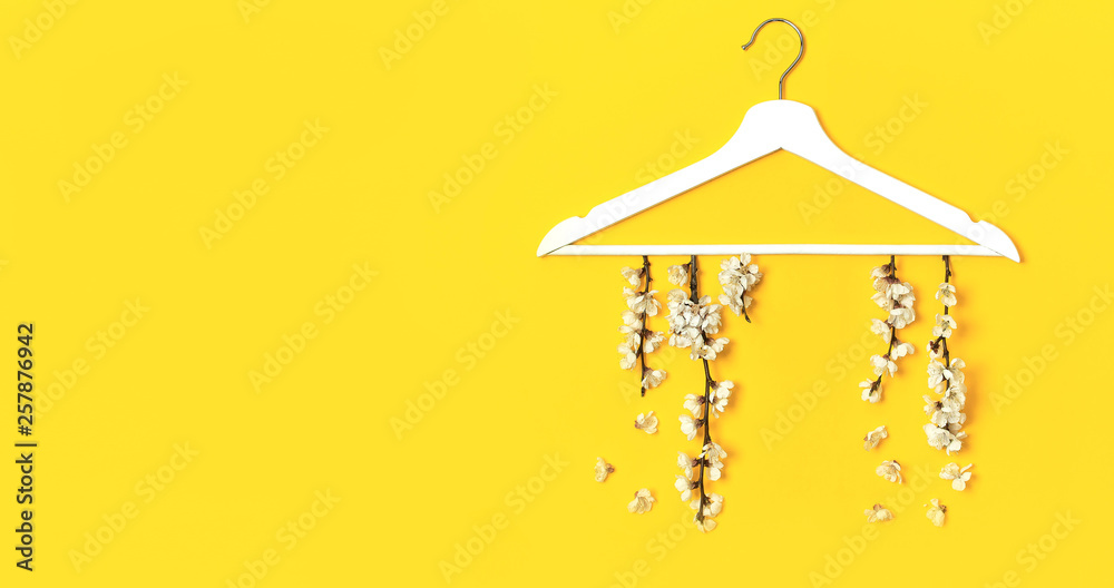 Spring flowering branch hang white wooden hangers on yellow background. Spring sale concept discount store shopping empty hanger promo design. Creative fashion banner. Flat lay top view copy space. Spring flowering branch hang white wooden hangers on yellow background. Spring sale concept discount store shopping empty hanger promo design. Creative fashion banner. Flat lay top view copy space.