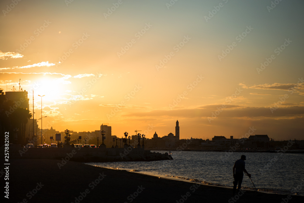 Panoramic view of cityscape in Bari, Italy. Romantic, calm, relaxing evening at the beach or city. Silhouette of cityscape. Sun is setting over old town.  