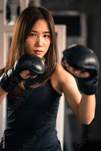 Attractive female boxer training with kick boxing at gym with blackgloves. © ic36006