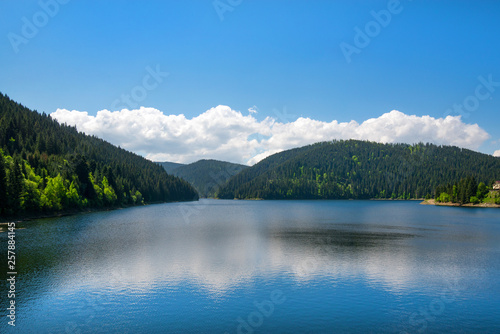 Fototapeta Naklejka Na Ścianę i Meble -  Beautiful mountain landscape with lake and reflections in water in summer. Tiny house or hotel on side of river. Concept of traveling. Clean environment. 