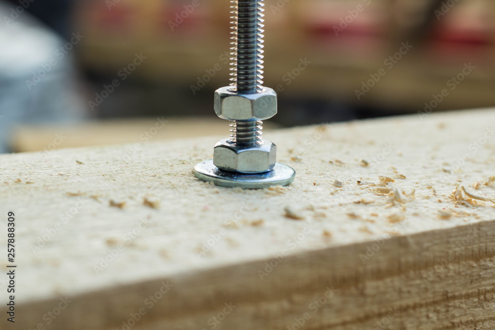 Bolt and nut twisted into a wooden board Bolt and nut twisted into a wooden board