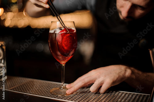 Bartender adding to a delicious cocktail red slice decor