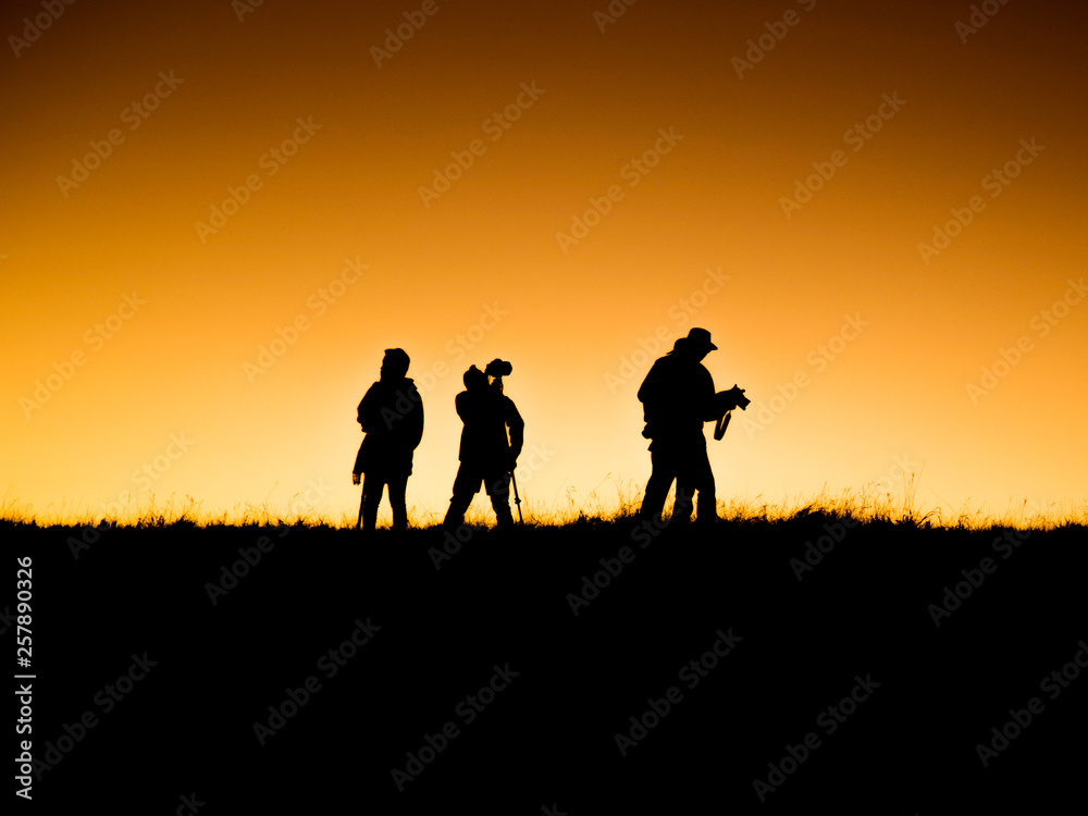 Silhouettes group of people on  mountain with sunset