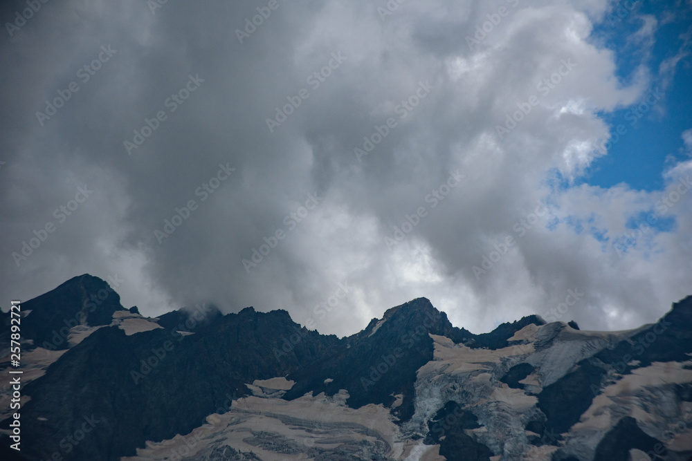 Massive peaks of the Caucasus Mountains in the snow in the surroundings of dombai in the clouds. Summer day. Massive peaks of the Caucasus Mountains in the snow in the surroundings of dombai in the clouds. Summer day.