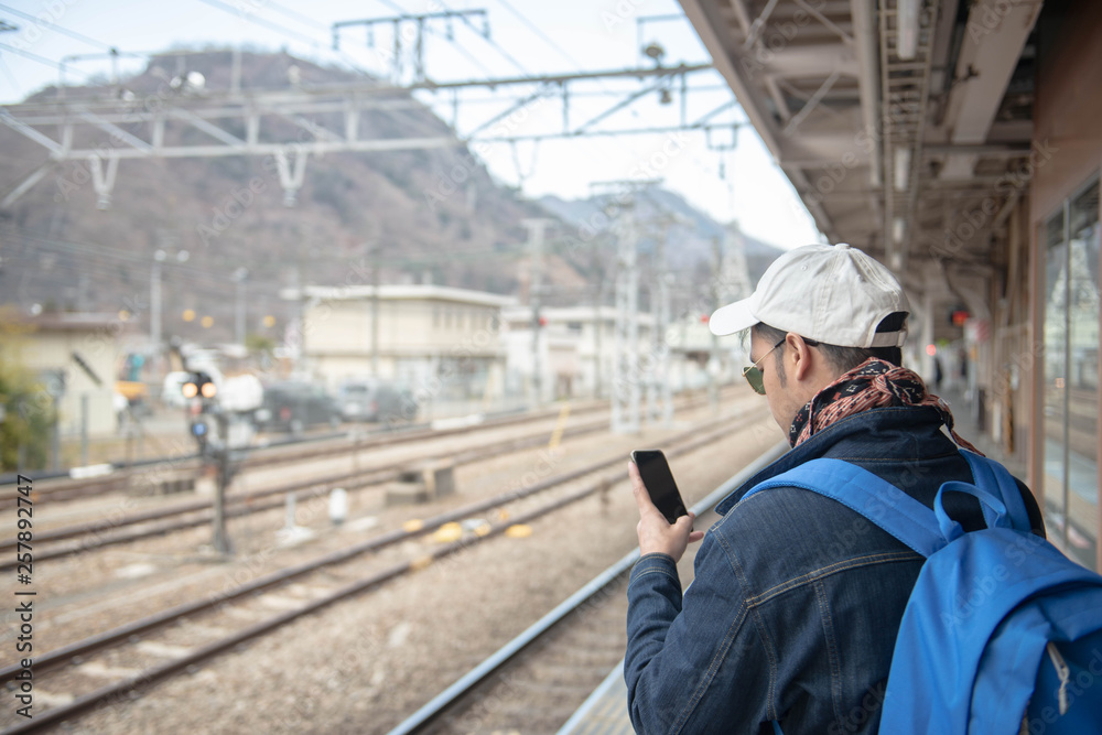 Closeup of man is reading text message on mobile phone are using gadgets during recreation time in train station