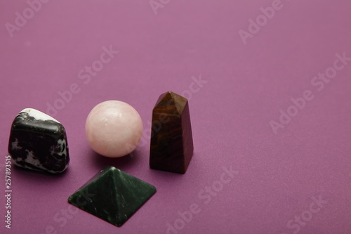 Magic stones and crystals of different shapes and colors lying in bulk on a bardic background.