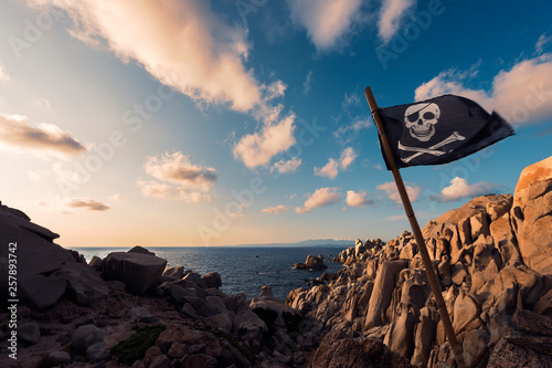 Fotografia coastal landscape of rocks with jolly roger flag