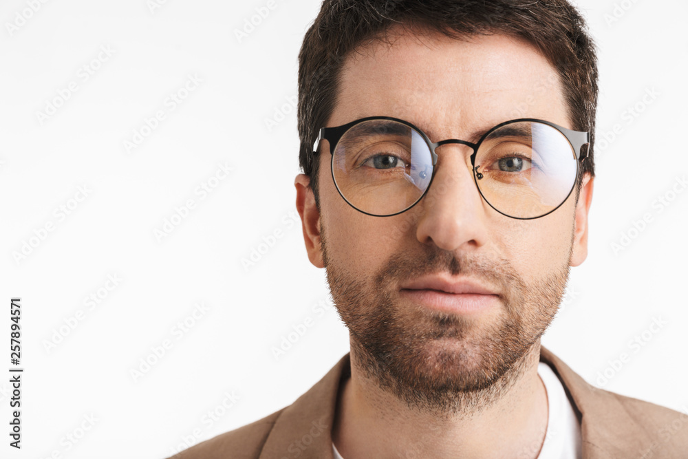 Image of unshaved man 30s with stubble wearing jacket and eyeglasses posing on camera Image of unshaved man 30s with stubble wearing jacket and eyeglasses posing on camera