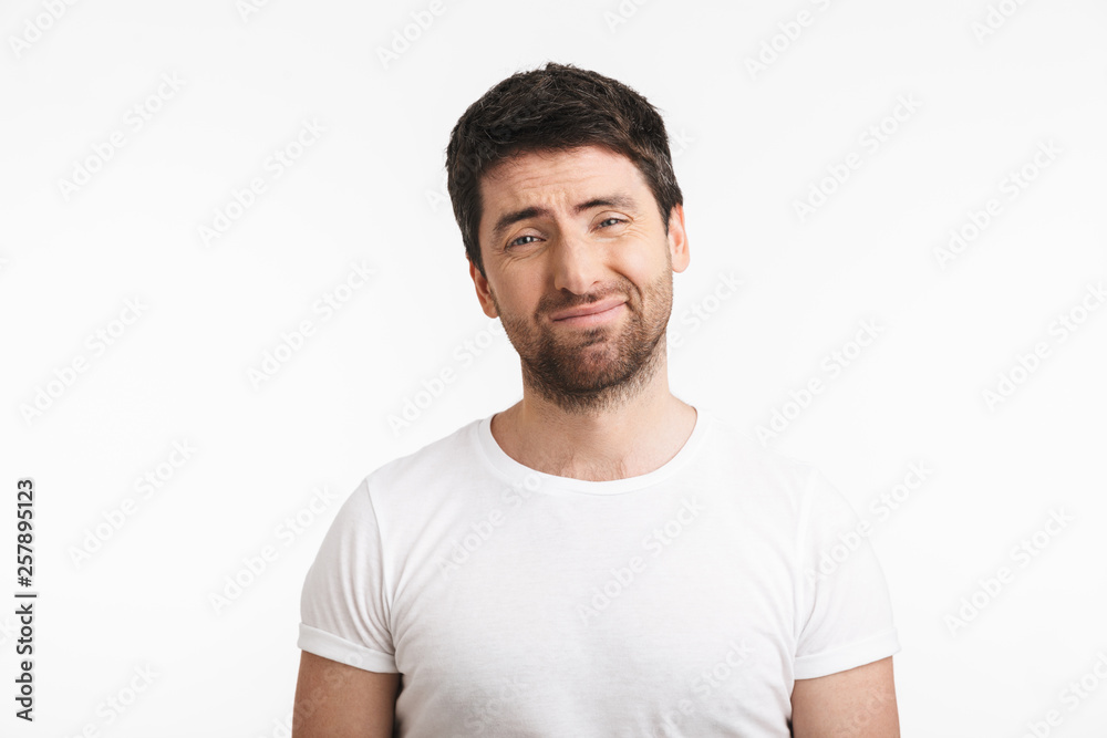 Image of unsure man 30s with bristle in casual t-shirt frowning and grimacing Image of unsure man 30s with bristle in casual t-shirt frowning and grimacing