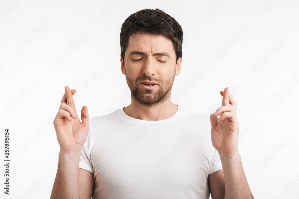 Image of upset man 30s with bristle in casual t-shirt keeping fingers crossed and making a wish Image of upset man 30s with bristle in casual t-shirt keeping fingers crossed and making a wish