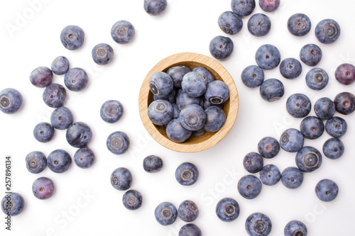 Lot of whole fresh sweet purple blueberry american with wooden bowl flatlay isolated on white background
