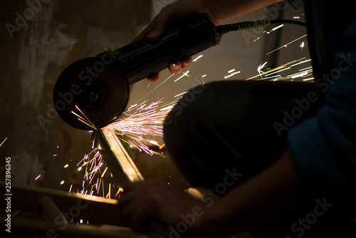Man grinding metal during renovation work at construction site, home or apartment. Industrial worker sawing. Concept of dangerous job. Flame sparks all around. 