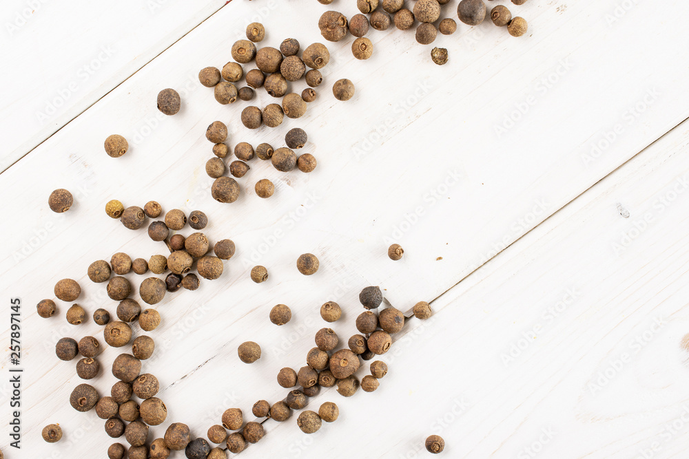 Lot of whole dry brown allspice berries flatlay on white wood Lot of whole dry brown allspice berries flatlay on white wood