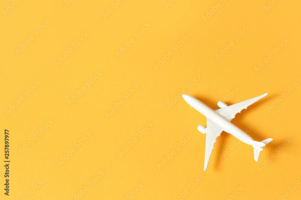 Miniature toy airplane on yellow background. Trip by airplane.