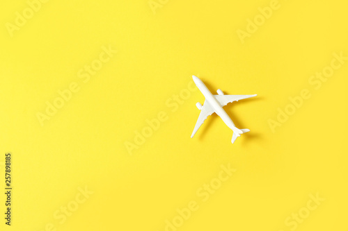 Fototapeta Miniature toy airplane on yellow background. Trip by airplane.