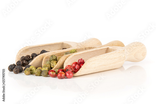 Lot of whole peppercorns of four colors with wooden scoop isolated on white background photo