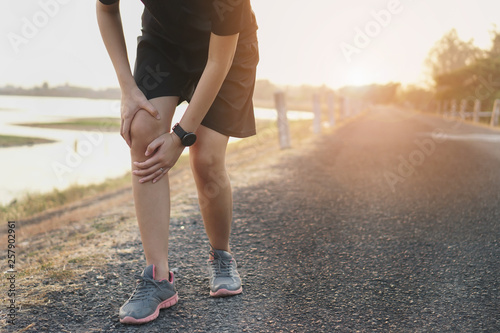 Runners leg pain, man holding sore and over trained painful leg muscle or cramp .Injured over trained person when exercising or running jogging outdoors.