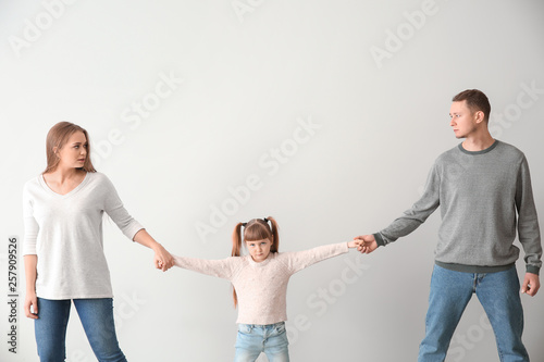 Divorced parents arguing about child custody on light background