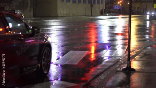 Chicago Illinois/United States March 24th 2019:  person walking in the middle of the night after a light rain as the street lights illuminate the concrete pavement. the car passing by driving home.