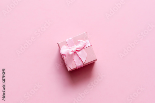 Pink gift box with bow on pink pastel background. Festive backdrop. Top view. Copy space.
