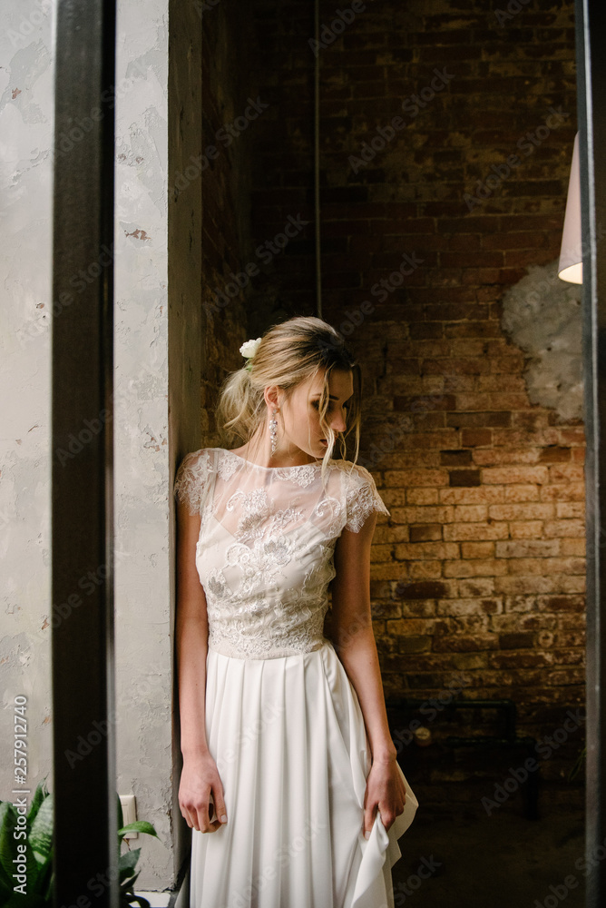 Model posing in a white long wedding dress indoors by the window. Advertising of wedding dresses Model posing in a white long wedding dress indoors by the window. Advertising of wedding dresses