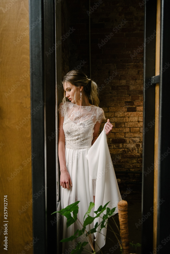 Model posing in a white long wedding dress indoors by the window. Advertising of wedding dresses Model posing in a white long wedding dress indoors by the window. Advertising of wedding dresses