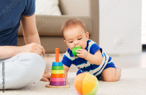 family, fatherhood and childhood concept - happy baby boy with father and toy pyramid at home