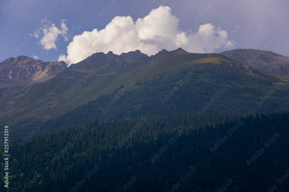 Large panorama Massive Caucasian mountains in the surroundings of dombai in the clouds. Summer day.