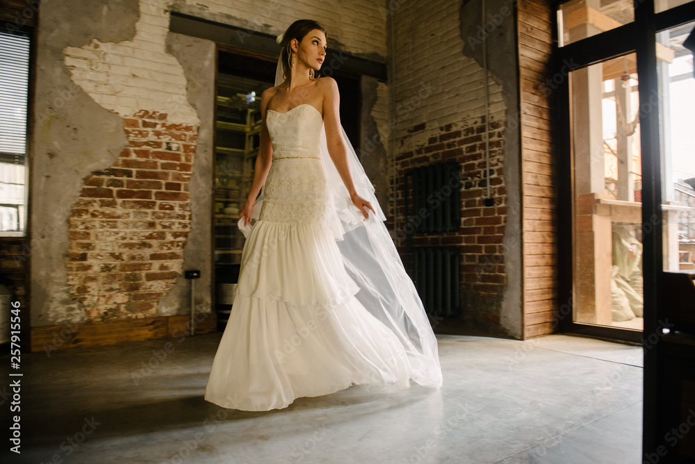 Model posing in a white long wedding dress indoors by the window. Advertising of wedding dresses Model posing in a white long wedding dress indoors by the window. Advertising of wedding dresses