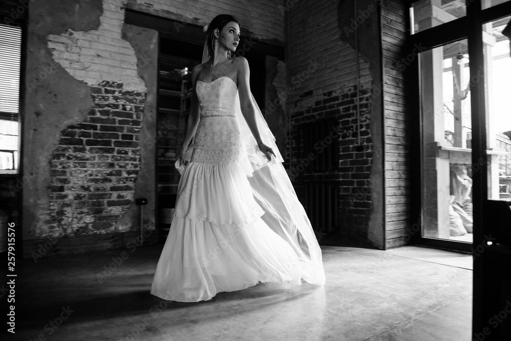 Model posing in a white long wedding dress indoors by the window. Advertising of wedding dresses Model posing in a white long wedding dress indoors by the window. Advertising of wedding dresses