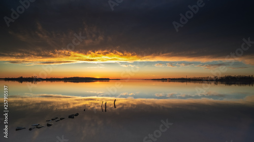 Atmospheric sunset above mirroring water surface with threatening clouds and an impressive landscape © fotografiecor