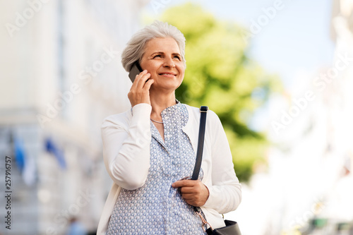 Fototapeta Naklejka Na Ścianę i Meble -  retirement, communication and old people concept - happy senior woman calling on smartphone in summer city