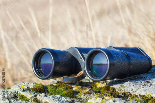 Binoculars on the stone in the steppe in the summer. This is important equipment for the traveler. photo