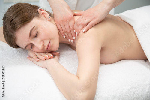 close-up masseur hands doing back massage in spa center. high key photo