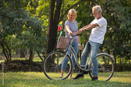 Happy senior couple relaxing at park walking with bike and talking together in morning time. old people in the autumn park . Elderly resting .mature relationships. family. romantic