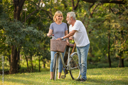 Happy senior couple relaxing at park walking with bike and talking together in morning time. old people in the autumn park . Elderly resting .mature relationships. family. romantic