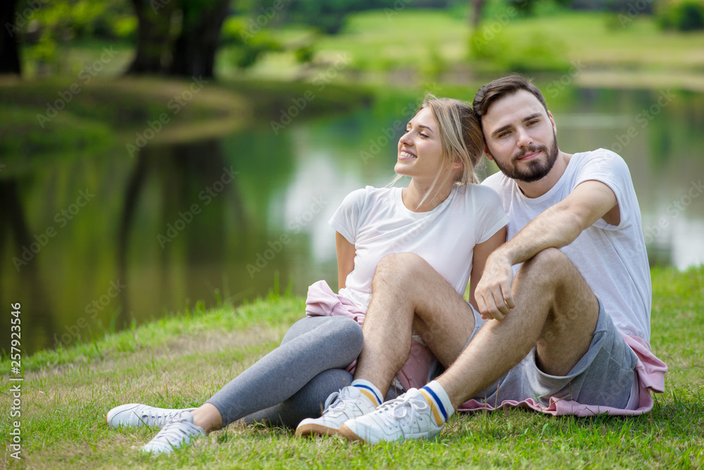 Happy young couple loving fitness in sportswear relaxing at park together in morning time. sport people sitting taking a break after exercises. resting . relationships. training,workout Happy young couple loving fitness in sportswear relaxing at park together in morning time. sport people sitting taking a break after exercises. resting . relationships. training,workout