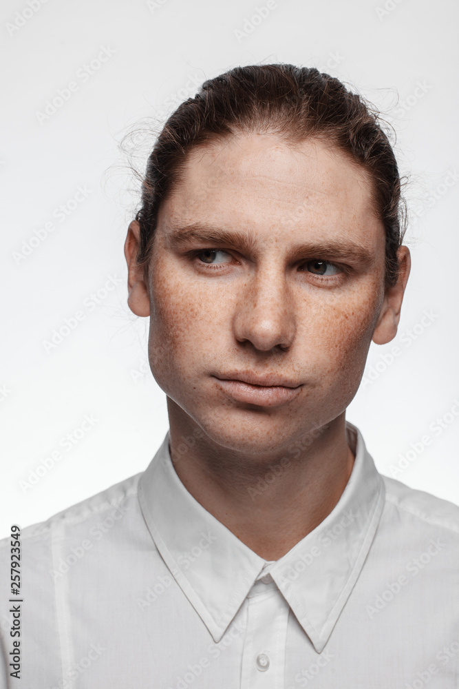 Portrait of a handsome long-haired man with drawn hair and freckles dressed in a white shirt Portrait of a handsome long-haired man with drawn hair and freckles dressed in a white shirt
