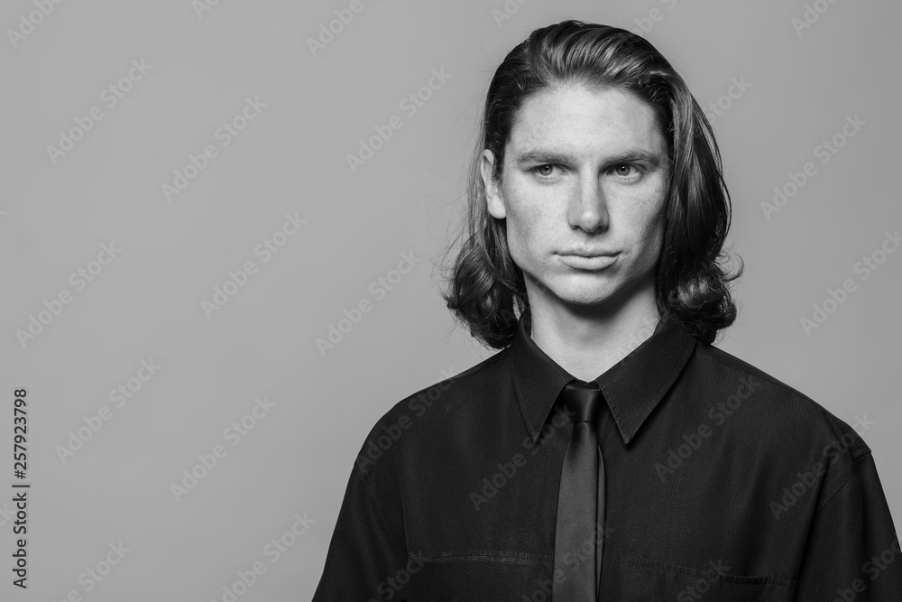Portrait of a man with long hair and freckles, dressed in a black shirt and black tie Portrait of a man with long hair and freckles, dressed in a black shirt and black tie