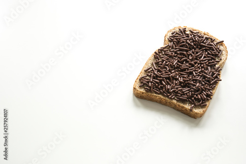 slice of bread with typical dutch chocolate hail, hagelslag . Against white background, space for text photo