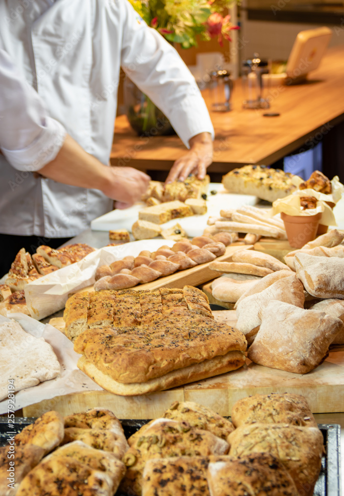 Assortment of artisian breads with hands of chef in background