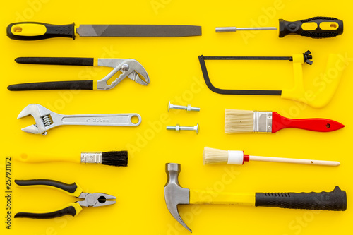 constructor desk with set of building implements and brushes yellow background top view pattern