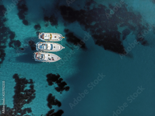 Fotografie Aerial view of three white yatches anchored together over crystal clear water