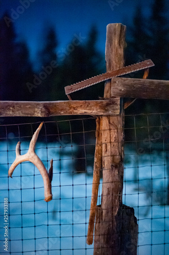 Antler and garden tool on fence at night
