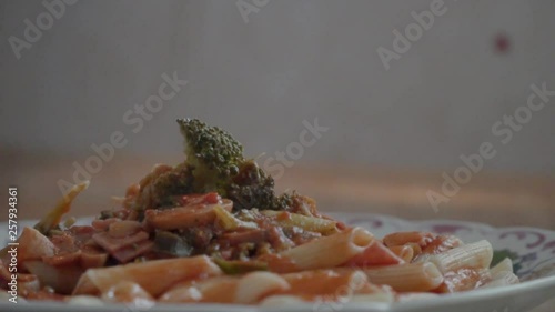 Penne with tomato sauce pork panceta broccoli and mashrooms served to the plate and ready to be placed to the family lunch table