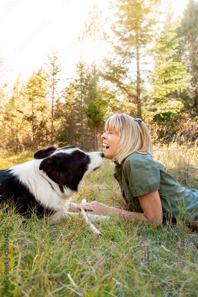 Smiling woman with black and white dog on grassy landscape Smiling woman with black and white dog on grassy landscape